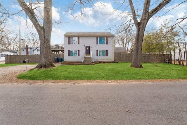 split foyer home with entry steps, a front yard, and fence