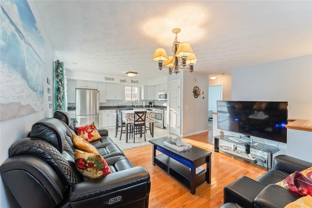 living area featuring an inviting chandelier, light wood-style flooring, and baseboards