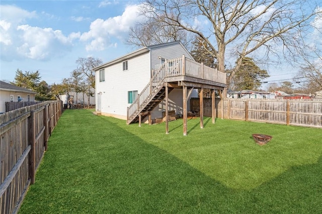 rear view of house featuring a fire pit, a lawn, a fenced backyard, stairway, and a wooden deck