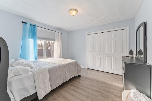 bedroom with light wood-type flooring, baseboards, and a closet