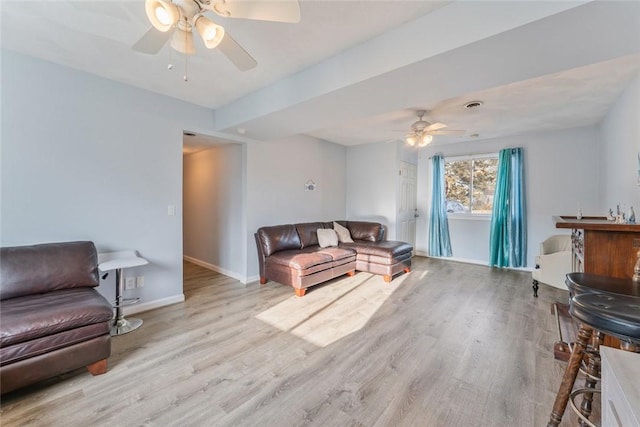 living room with a ceiling fan, baseboards, and wood finished floors