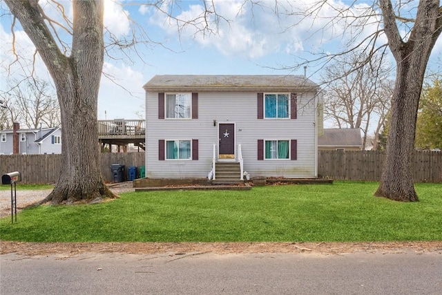 raised ranch featuring a front lawn and fence