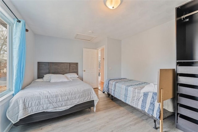 bedroom featuring attic access, baseboards, and wood finished floors