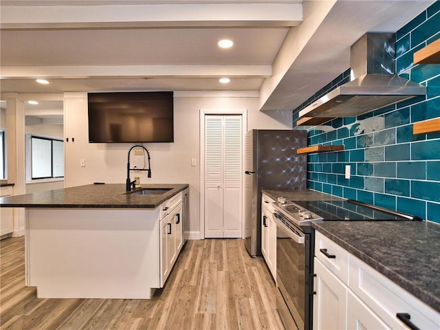 kitchen featuring light wood finished floors, white cabinets, stainless steel appliances, wall chimney range hood, and a sink