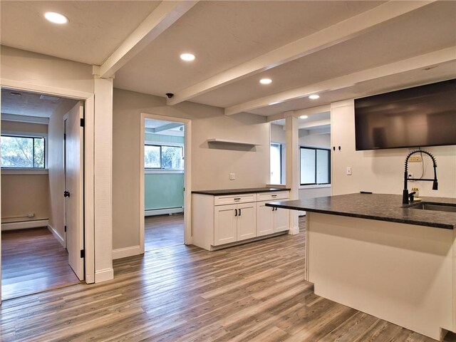 kitchen with open shelves, baseboard heating, a sink, and beam ceiling