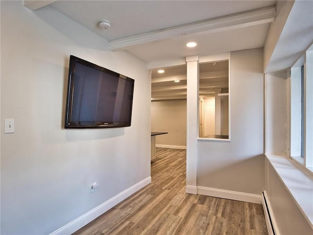 spare room with a baseboard radiator, baseboards, wood finished floors, and recessed lighting