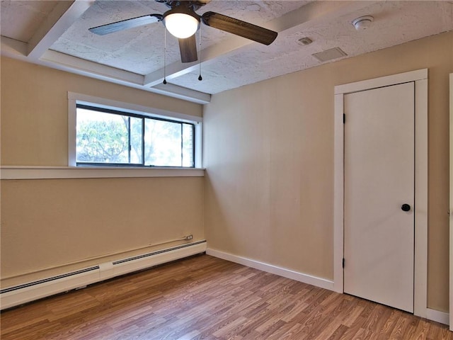 spare room with a baseboard heating unit, beamed ceiling, baseboards, and wood finished floors