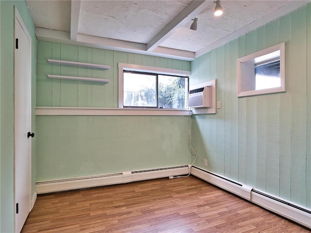 spare room featuring a baseboard heating unit, beam ceiling, a wall unit AC, and wood finished floors