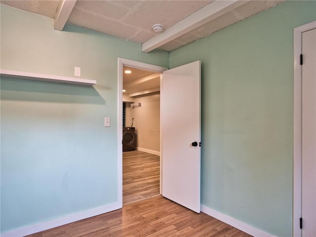 spare room featuring baseboards, washer / clothes dryer, and wood finished floors