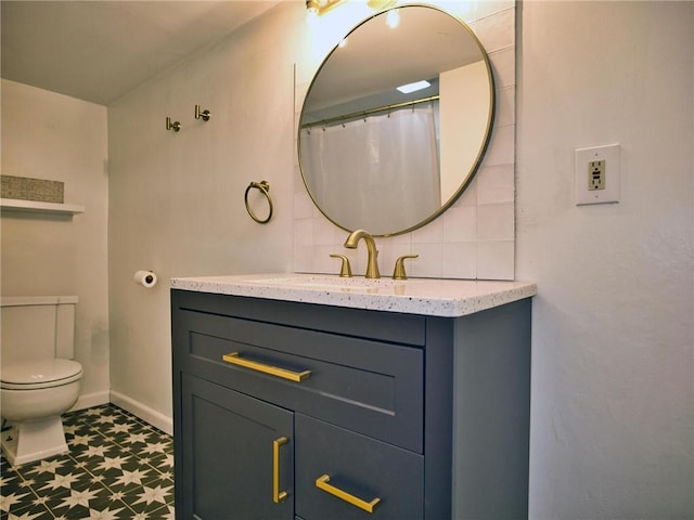 bathroom featuring backsplash, toilet, vanity, baseboards, and tile patterned floors