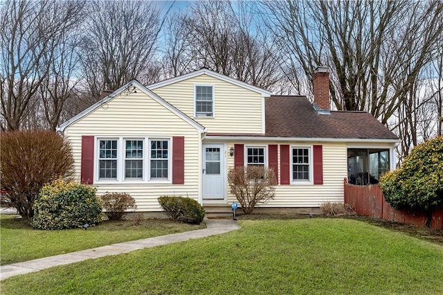 traditional-style house featuring entry steps, a chimney, a front lawn, and roof with shingles