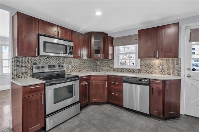 kitchen featuring a sink, backsplash, appliances with stainless steel finishes, and light countertops