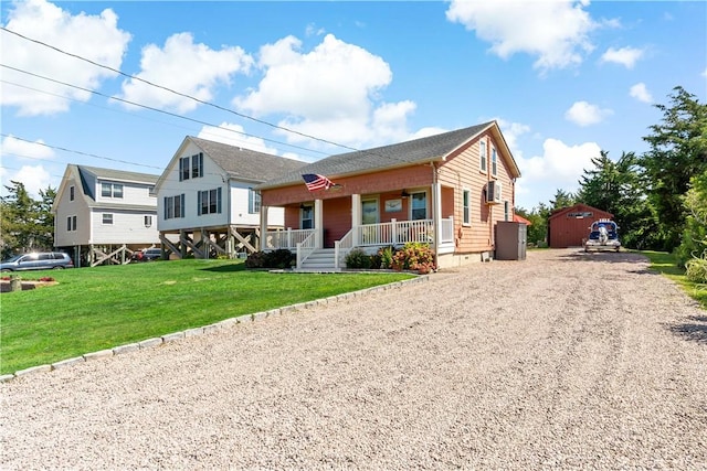 view of front of home featuring a front lawn, covered porch, an outdoor structure, and gravel driveway