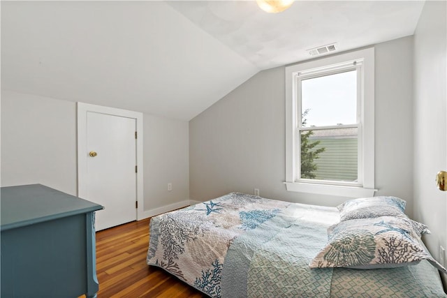 bedroom featuring lofted ceiling, baseboards, visible vents, and wood finished floors