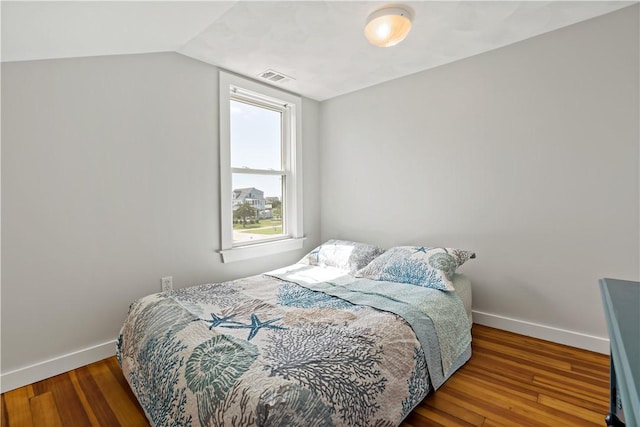 bedroom with lofted ceiling, visible vents, baseboards, and wood finished floors