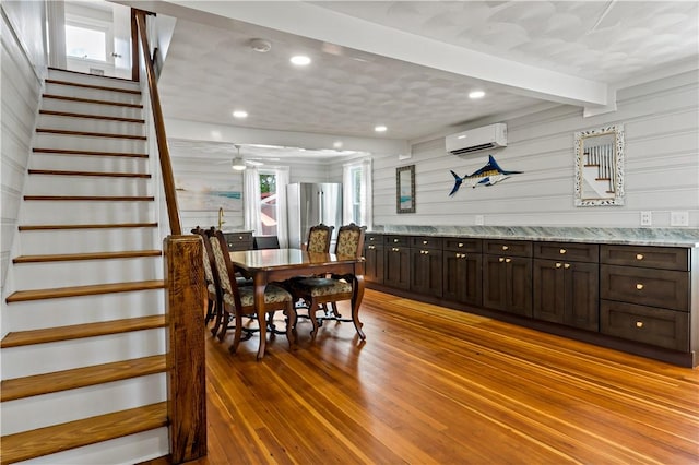 dining space featuring recessed lighting, an AC wall unit, stairway, beam ceiling, and light wood finished floors