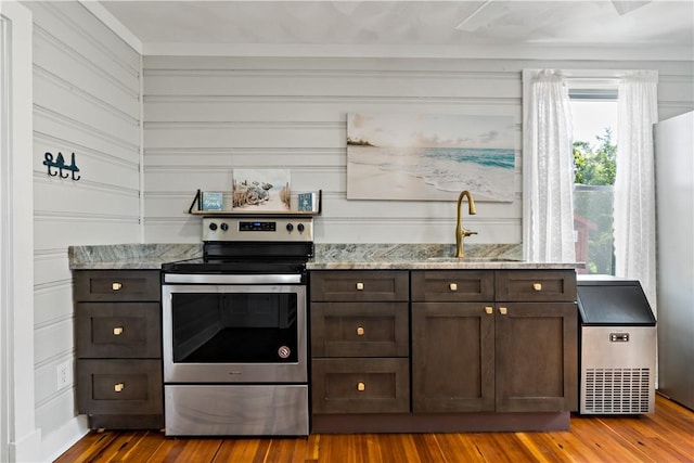 kitchen featuring a sink, dark brown cabinetry, stainless steel electric range oven, and wood finished floors