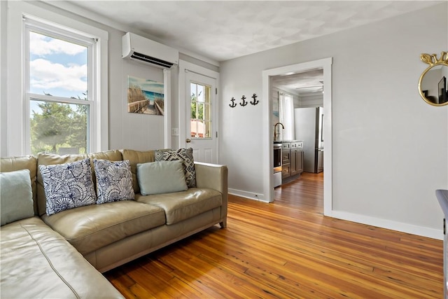 living room featuring a wall unit AC, light wood-style flooring, and baseboards