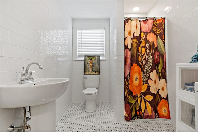 bathroom with toilet, curtained shower, and tile walls