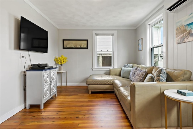 living area with ornamental molding, hardwood / wood-style floors, a wall mounted AC, and baseboards