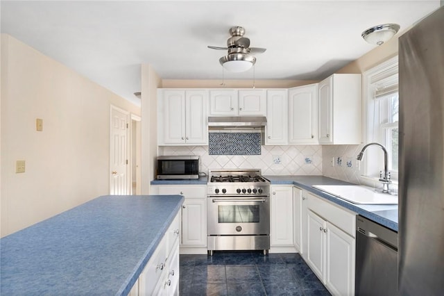 kitchen featuring under cabinet range hood, a sink, white cabinets, appliances with stainless steel finishes, and tasteful backsplash