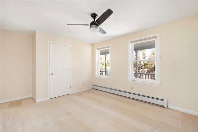 carpeted spare room with a baseboard radiator, a ceiling fan, and baseboards