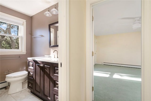 bathroom with a ceiling fan, toilet, marble finish floor, vanity, and a baseboard heating unit