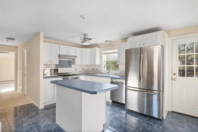 kitchen featuring white cabinets, appliances with stainless steel finishes, baseboard heating, under cabinet range hood, and a sink