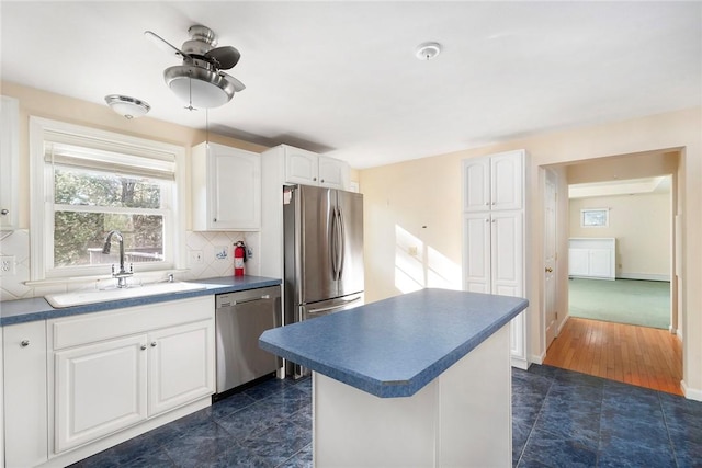 kitchen with a sink, white cabinetry, appliances with stainless steel finishes, decorative backsplash, and dark countertops