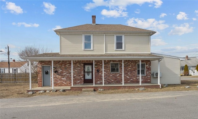 view of front facade with a chimney, fence, a porch, and brick siding