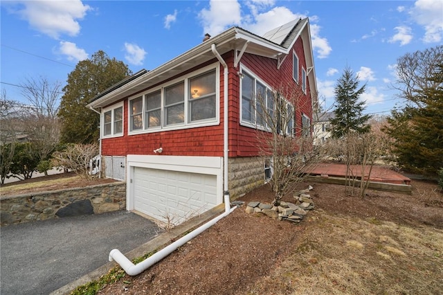 view of side of home with driveway and an attached garage