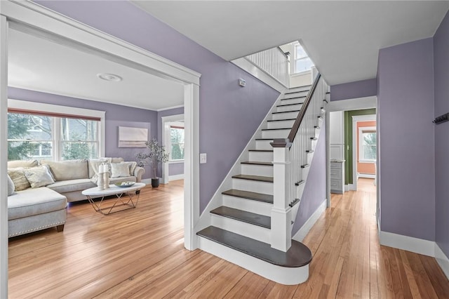 staircase featuring a healthy amount of sunlight, baseboards, and wood finished floors