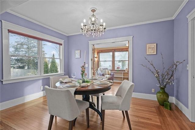 dining area with light wood-style floors, baseboards, crown molding, and an inviting chandelier