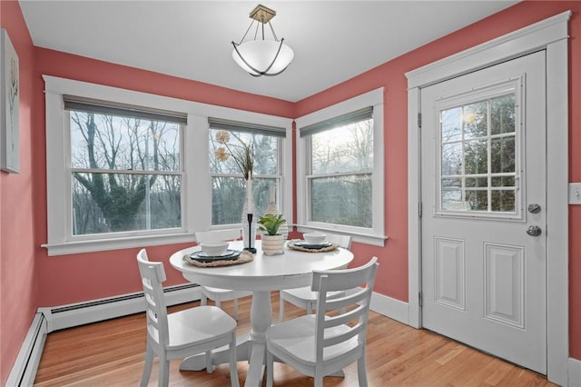 dining room with baseboard heating, baseboards, and light wood finished floors