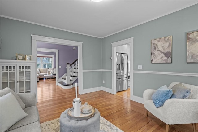 living room featuring baseboards, stairway, wood finished floors, and ornamental molding