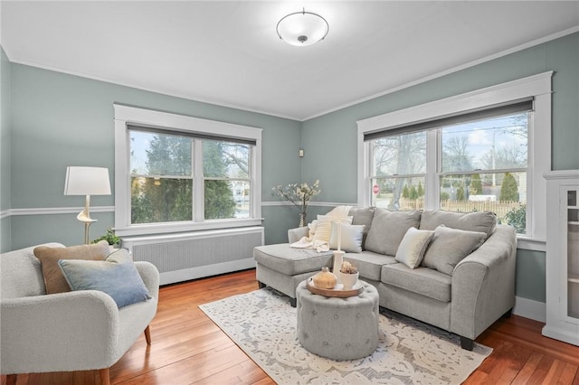 living area with radiator heating unit, wood finished floors, and crown molding