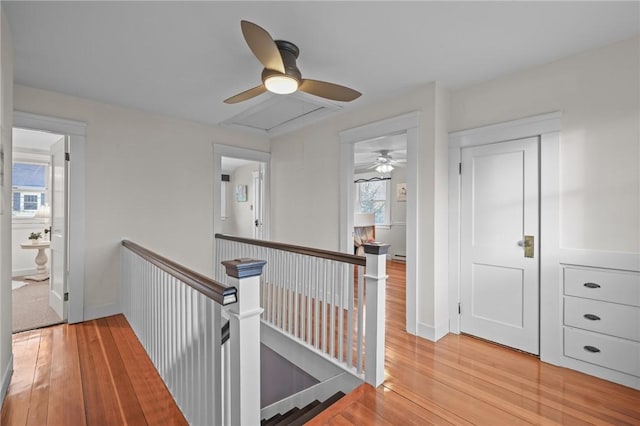 hall with light wood finished floors, baseboards, and an upstairs landing