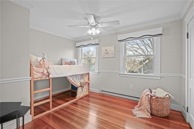 bedroom with a baseboard heating unit, wood finished floors, and crown molding