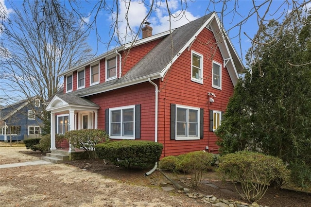 view of front of property with a shingled roof and a chimney