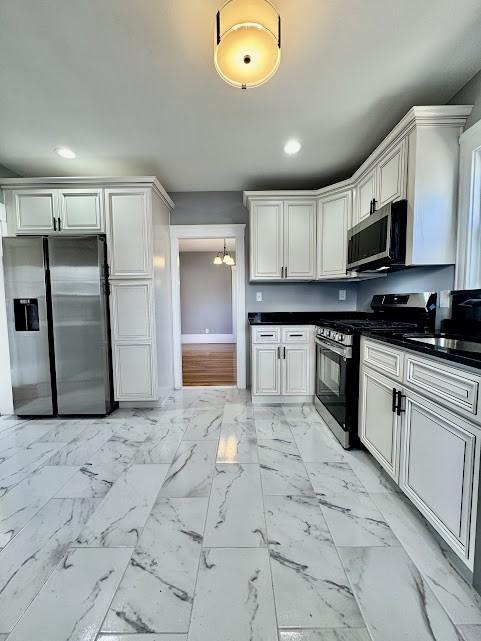 kitchen featuring recessed lighting, a sink, marble finish floor, appliances with stainless steel finishes, and dark countertops