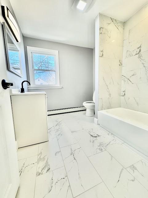 bathroom with a baseboard heating unit, marble finish floor, vanity, and toilet