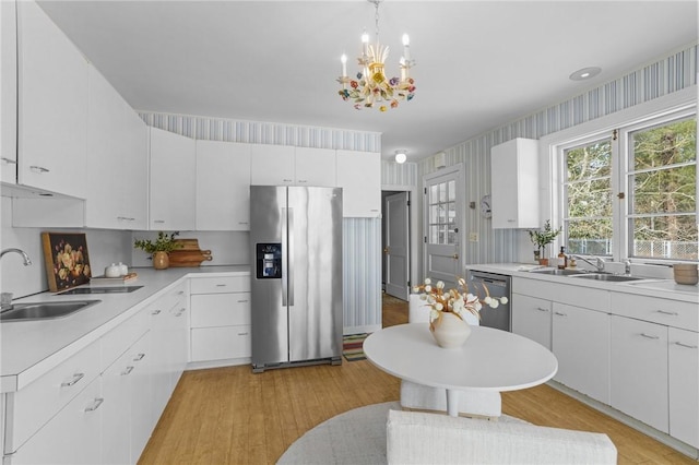 kitchen featuring stainless steel appliances, light countertops, a sink, and wallpapered walls