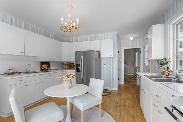 kitchen featuring appliances with stainless steel finishes, light wood-style floors, light countertops, and a sink