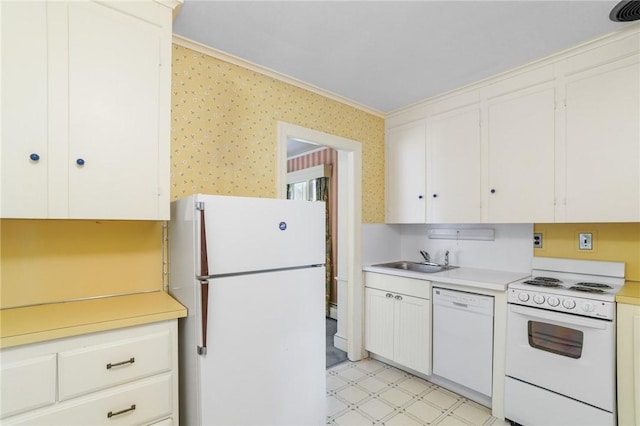 kitchen with light floors, light countertops, a sink, white appliances, and wallpapered walls