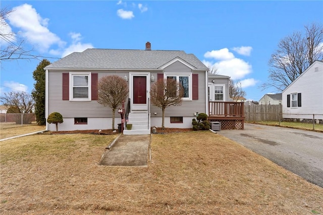 view of front of property with entry steps, roof with shingles, a front yard, and fence