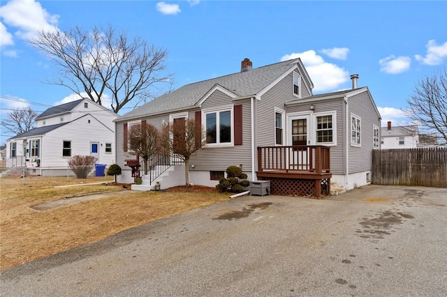 view of front of property featuring roof with shingles and fence