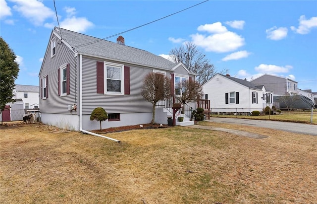 bungalow-style home featuring a front lawn, a chimney, a shingled roof, and fence