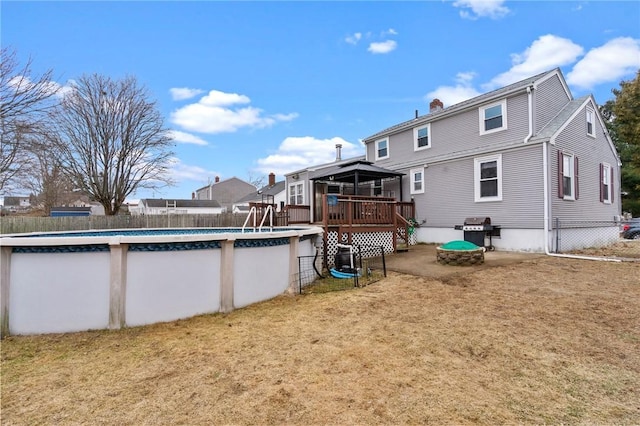 rear view of house with a fenced in pool, fence, a deck, and a lawn