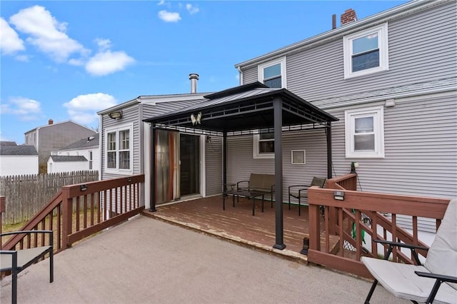 rear view of property featuring fence, a deck, and a gazebo