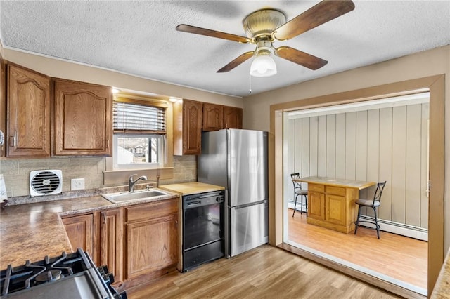 kitchen with a baseboard heating unit, freestanding refrigerator, a sink, light wood-type flooring, and dishwasher